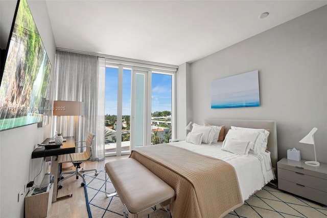 bedroom featuring access to outside, floor to ceiling windows, and light wood-style flooring