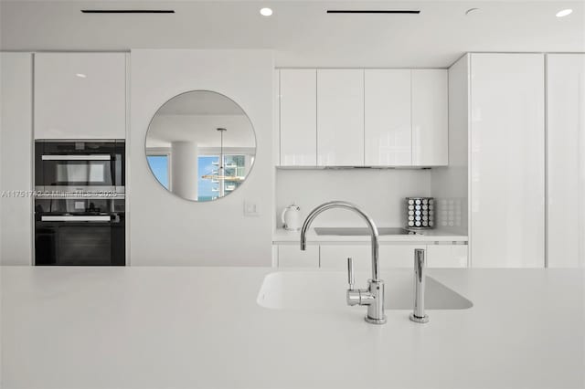 kitchen with dobule oven black, modern cabinets, light countertops, white cabinetry, and recessed lighting