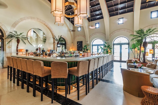 bar featuring a high ceiling, plenty of natural light, a dry bar, and finished concrete floors