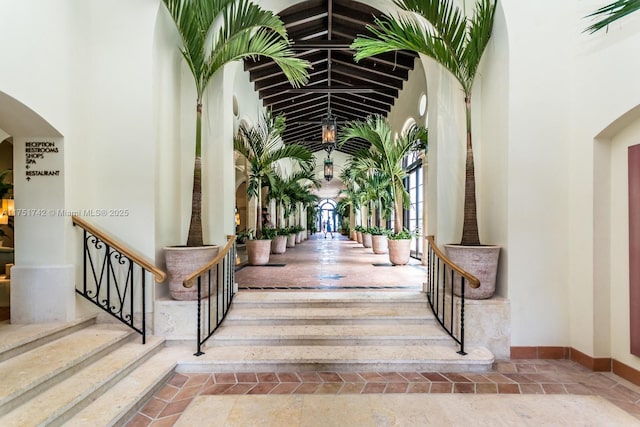 interior space featuring stairway, arched walkways, a towering ceiling, and baseboards