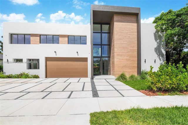 contemporary home featuring an attached garage, concrete driveway, and stucco siding