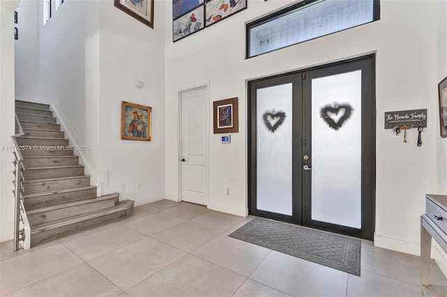 entryway with light tile patterned floors, baseboards, a high ceiling, stairs, and french doors