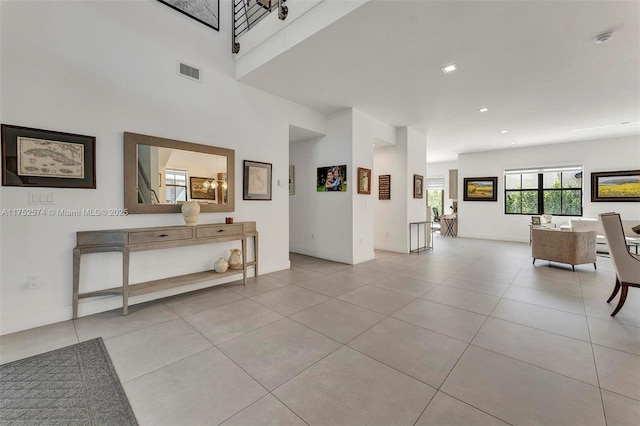 interior space with light tile patterned floors, baseboards, a high ceiling, and visible vents