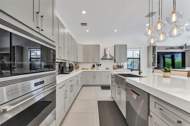 kitchen featuring gray cabinets, visible vents, light countertops, appliances with stainless steel finishes, and wall chimney range hood