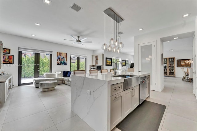 kitchen featuring a kitchen island with sink, visible vents, white cabinetry, open floor plan, and decorative light fixtures