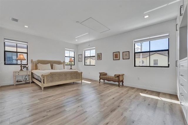 bedroom with light wood finished floors, attic access, multiple windows, and baseboards