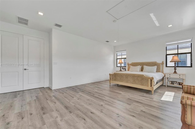 bedroom featuring attic access, light wood-type flooring, visible vents, and baseboards