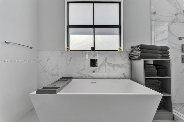 bathroom featuring marble finish floor and a soaking tub