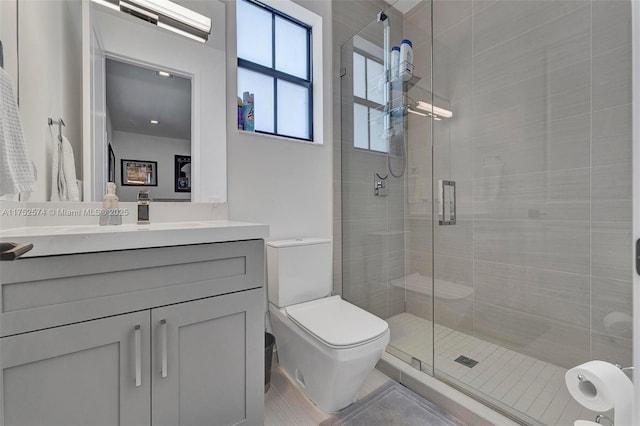 bathroom featuring toilet, a shower stall, and vanity