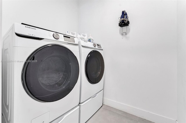 clothes washing area with laundry area, baseboards, and washing machine and clothes dryer