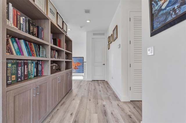 hallway with light wood finished floors, baseboards, and visible vents