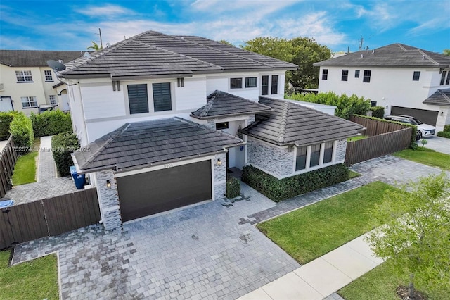 view of front of house with a fenced front yard, a tile roof, and decorative driveway