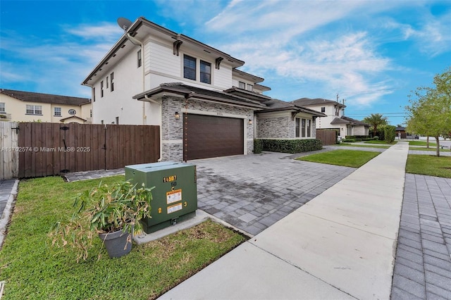 view of front of property featuring a garage, a front lawn, decorative driveway, and fence