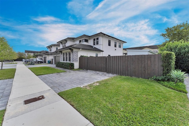 view of property exterior with a fenced front yard, decorative driveway, and a lawn