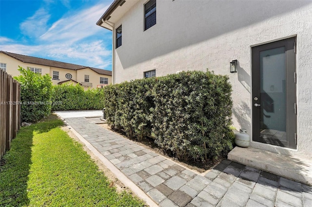 view of property exterior with a yard, a patio area, fence, and stucco siding