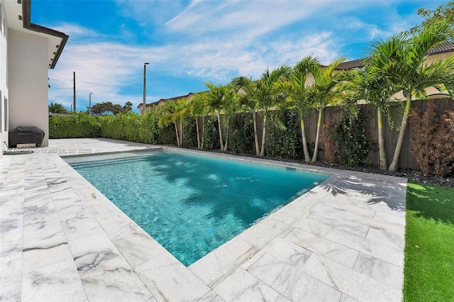 view of pool with a fenced backyard and a patio