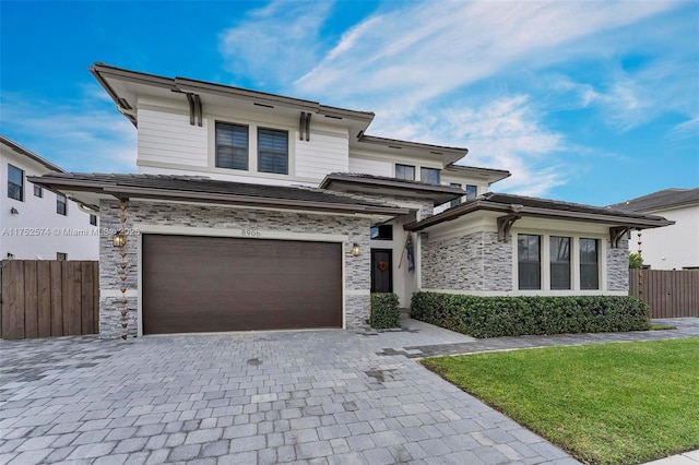 view of front of property featuring a garage, stone siding, decorative driveway, and fence