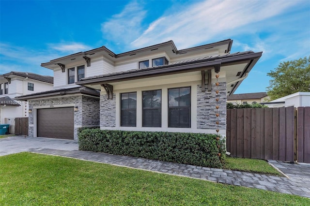 view of front of property with a garage, fence, stone siding, decorative driveway, and a front lawn