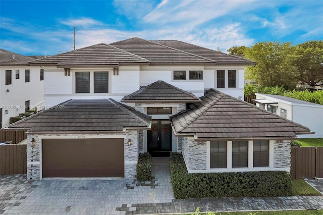 view of front of home featuring a garage, stone siding, fence, and decorative driveway