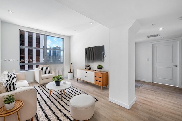 living room featuring light wood-type flooring, baseboards, visible vents, and recessed lighting