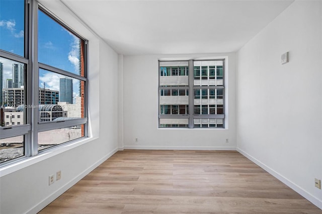111 E Flagler St Unit 704, Miami, FL 33131 - unfurnished room with light wood-style floors, a view of city, and baseboards
