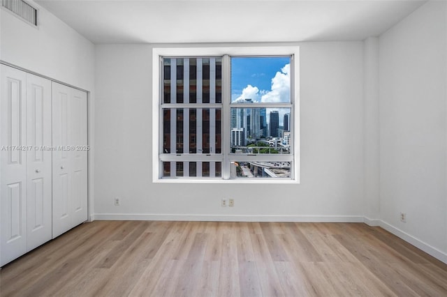 111 E Flagler St Unit 704, Miami, FL 33131 - unfurnished bedroom with light wood-type flooring, a closet, visible vents, and baseboards