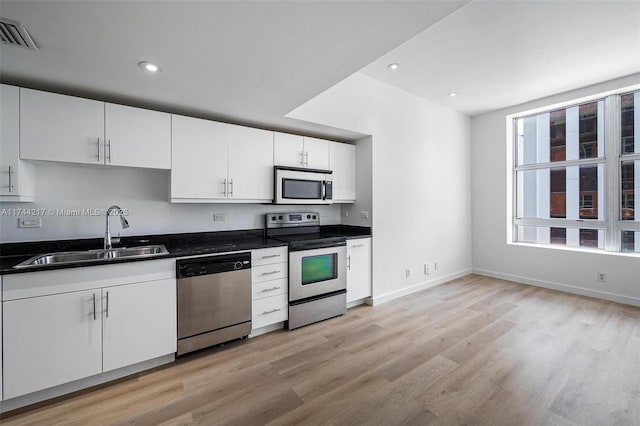 111 E Flagler St Unit 704, Miami, FL 33131 - kitchen with light wood finished floors, visible vents, appliances with stainless steel finishes, white cabinets, and a sink