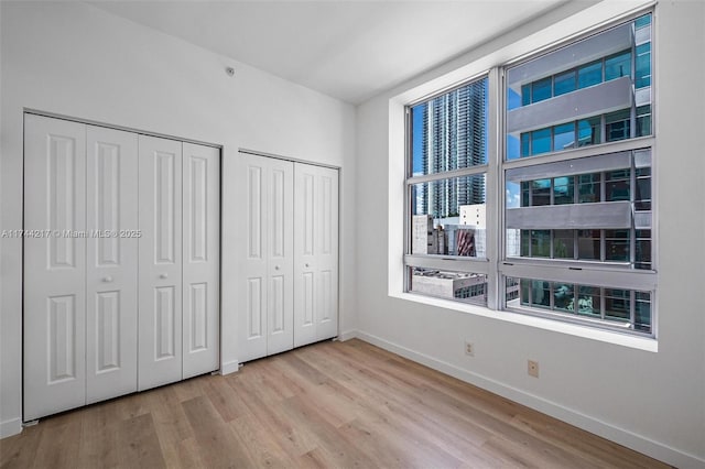 111 E Flagler St Unit 704, Miami, FL 33131 - unfurnished bedroom with light wood finished floors, baseboards, and multiple closets