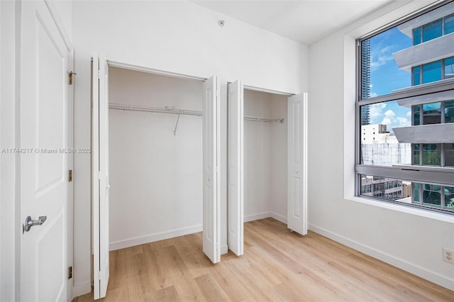 111 E Flagler St Unit 704, Miami, FL 33131 - unfurnished bedroom with multiple closets, light wood-type flooring, and baseboards
