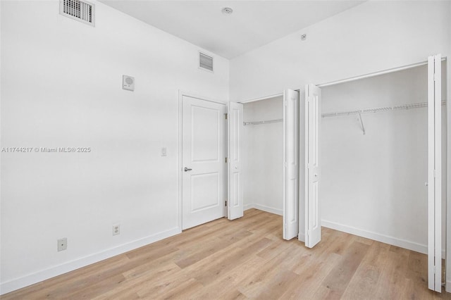 111 E Flagler St Unit 704, Miami, FL 33131 - unfurnished bedroom with visible vents, light wood-style flooring, and two closets