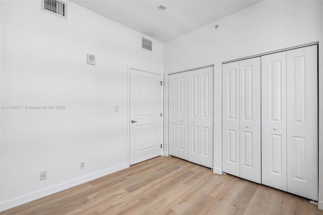 111 E Flagler St Unit 704, Miami, FL 33131 - unfurnished bedroom with light wood-type flooring, visible vents, and two closets