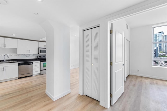 111 E Flagler St Unit 704, Miami, FL 33131 - kitchen featuring stainless steel appliances, dark countertops, white cabinets, and light wood-style flooring