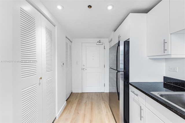 111 E Flagler St Unit 704, Miami, FL 33131 - kitchen with white cabinets, freestanding refrigerator, light wood-style floors, a sink, and recessed lighting