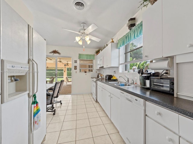 kitchen featuring dark countertops, visible vents, white cabinetry, a sink, and white appliances