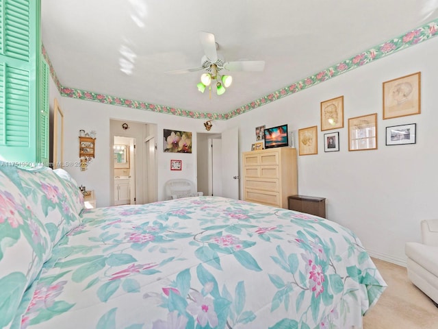 bedroom featuring light carpet, ensuite bath, baseboards, and a ceiling fan