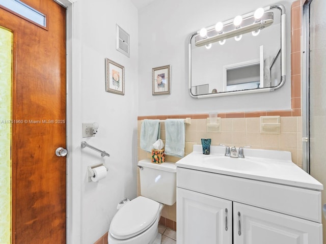 bathroom featuring tile walls, wainscoting, vanity, and toilet