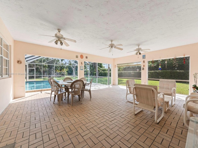 view of patio / terrace with glass enclosure, outdoor dining space, and a ceiling fan