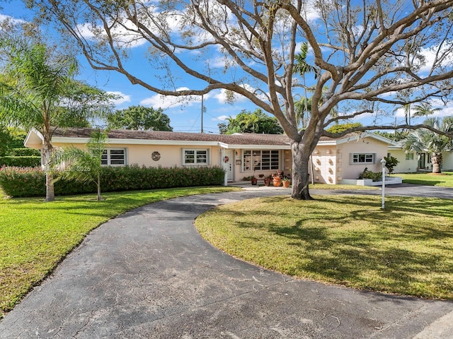 single story home with aphalt driveway, a front lawn, and stucco siding