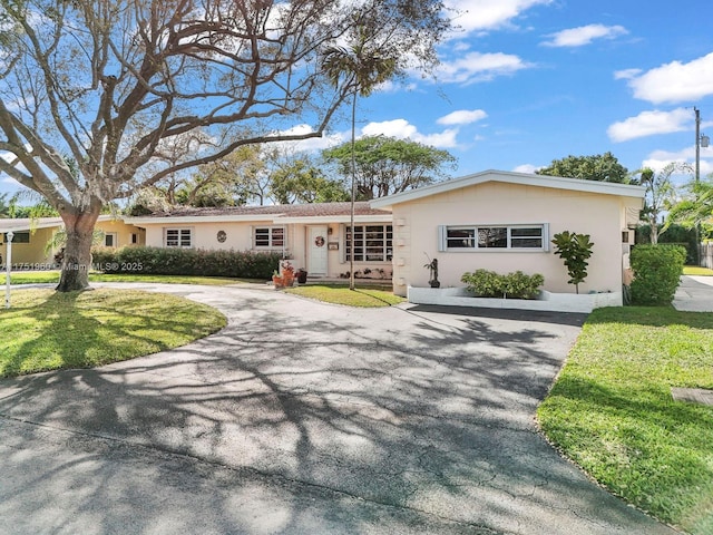 single story home featuring aphalt driveway, a front lawn, and stucco siding