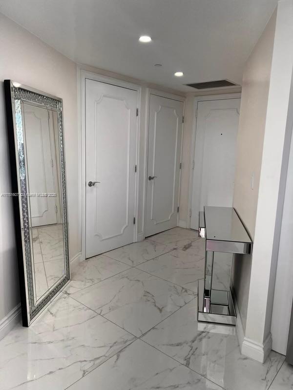 hallway featuring marble finish floor, baseboards, and recessed lighting