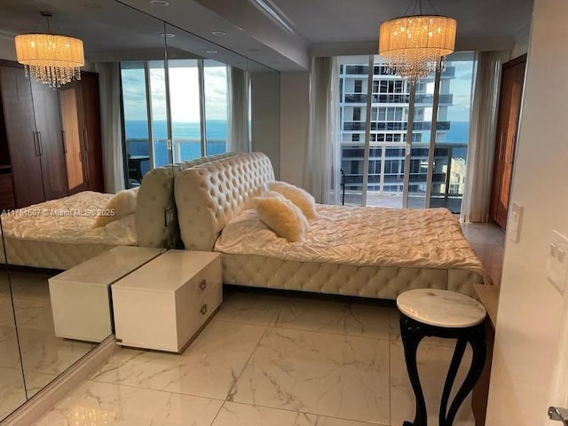 bedroom featuring marble finish floor, a water view, and a notable chandelier