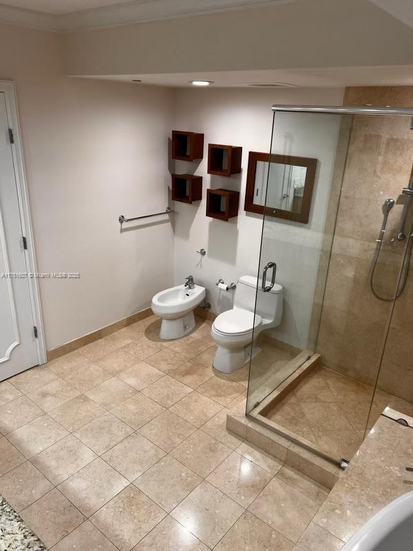 bathroom featuring baseboards, toilet, crown molding, a shower stall, and a bidet