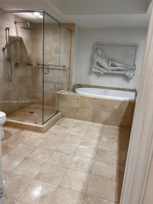 full bathroom featuring toilet, a stall shower, a bath, and tile patterned floors