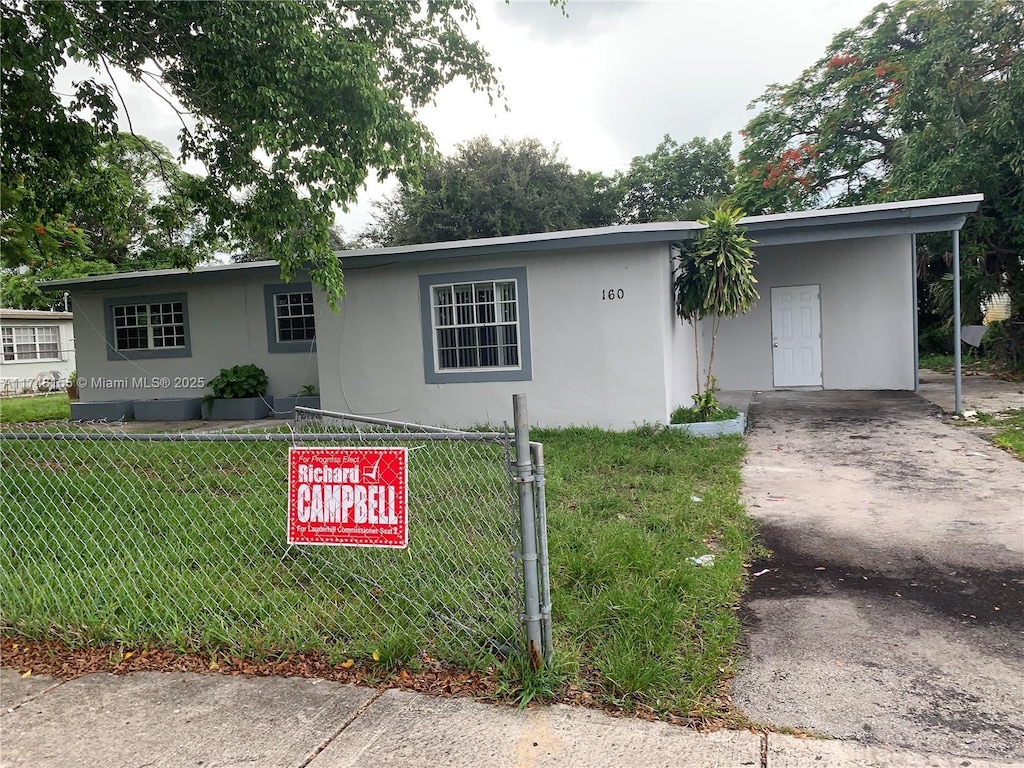 single story home featuring driveway, a front lawn, and stucco siding