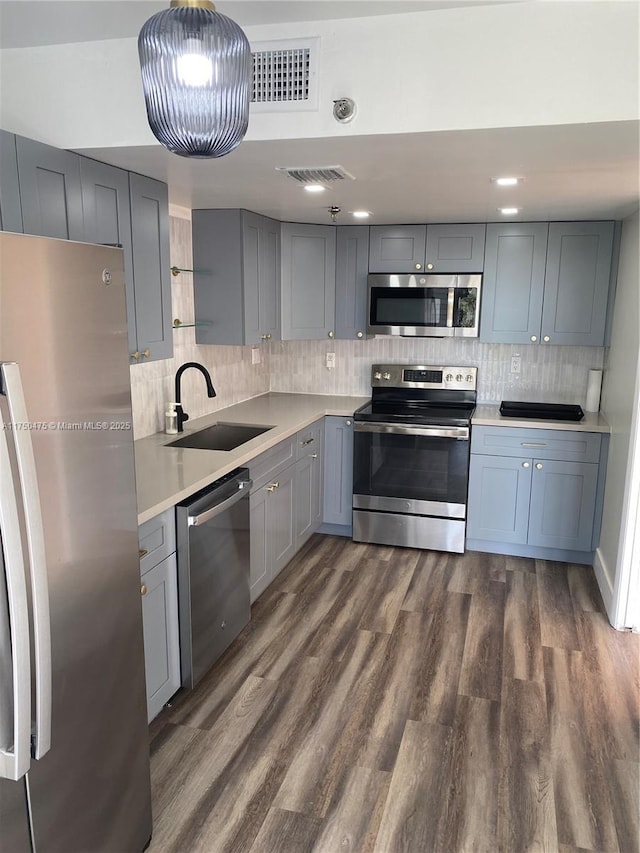 kitchen with dark wood-style flooring, a sink, visible vents, light countertops, and appliances with stainless steel finishes