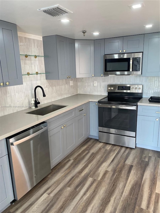 kitchen with dark wood-style floors, stainless steel appliances, light countertops, visible vents, and a sink