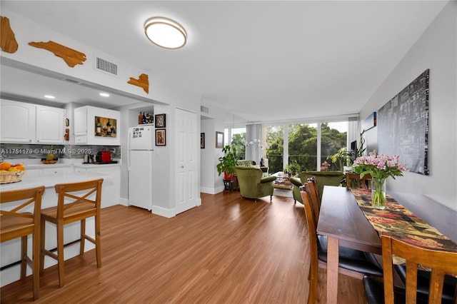 interior space with light wood-style flooring, white cabinetry, light countertops, backsplash, and freestanding refrigerator