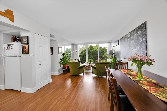 living area with light wood-style flooring, expansive windows, visible vents, and baseboards