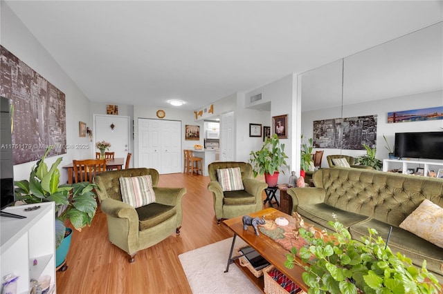 living area with visible vents and wood finished floors