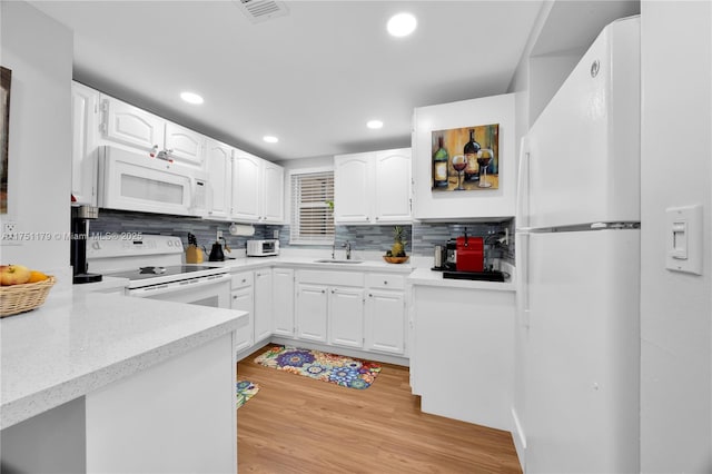 kitchen featuring light countertops, backsplash, white cabinets, a sink, and white appliances